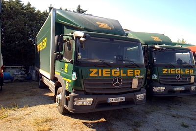 deux camions verts garés l'un à côté de l'autre sur un parking
