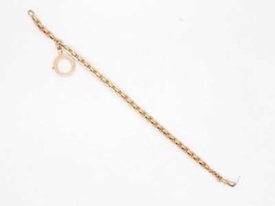 un gros plan d'un bracelet en chaîne dorée sur lequel est enfilée une bague