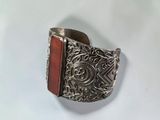 un gros plan d'une bague en argent sertie d'une pierre rouge