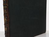 un vieux livre posé sur une table blanche à côté d'un mur blanc