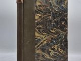 un livre à la couverture marron posé sur une surface blanche