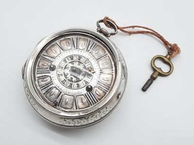 une montre de poche en argent à laquelle est attachée une clé