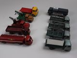 Plusieurs camions miniatures sont alignés sur une surface blanche