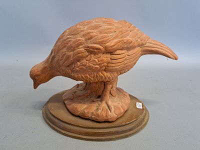 statue représentant un oiseau, posée sur un socle en bois, sur une surface blanche