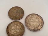 three old coins sitting on top of a white surface