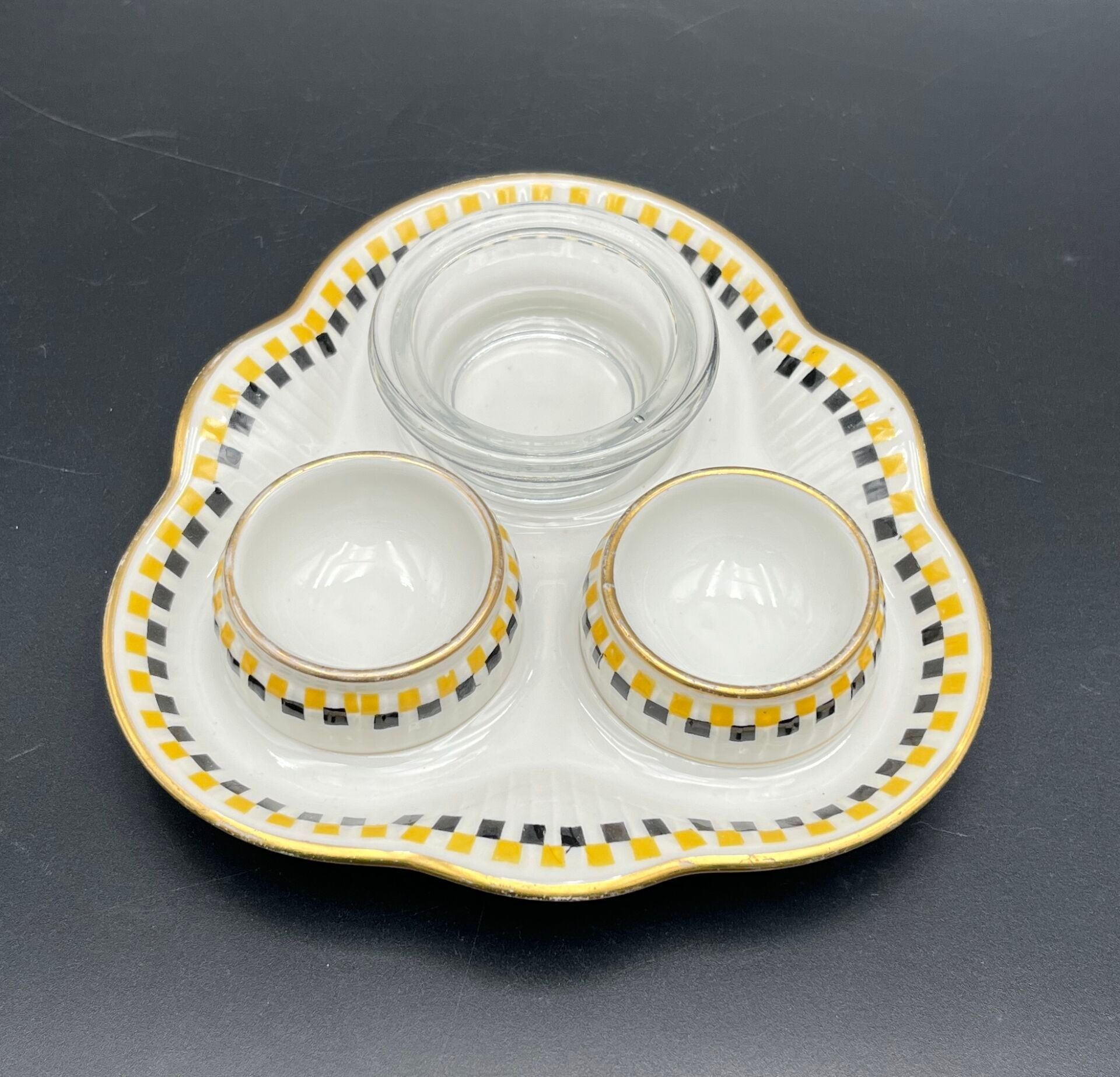 FRANCE - MEHUN Ensemble de deux coquetiers et leur coupelle en porcelaine à fond blanc et décor de petits carrés jaun...