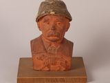 statue d'un homme coiffé d'un chapeau, posée sur un socle en bois