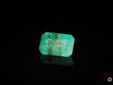 a close up of a green emerald stone on a black surface