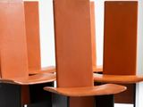 four chairs with orange leather seats sit in a row on a white surface
