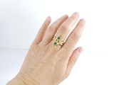 a woman ' s hand holding a green and white ring