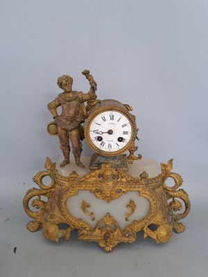 a gold clock with a statue on top of it