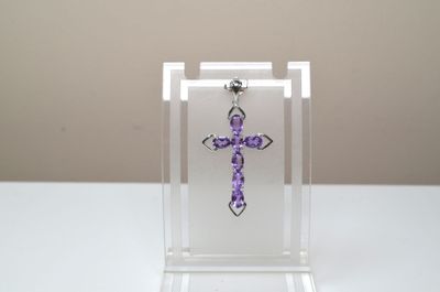 une croix violette posée dans une vitrine transparente posée sur une table