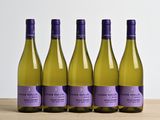 Quatre bouteilles de vin blanc sont alignées sur une table en bois