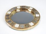 a gold plate with a mirror on it on a white surface