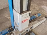 a close up of a fork lift with a red car in the background
