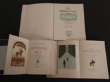 Trois livres sont ouverts sur une table noire, sur fond noir.