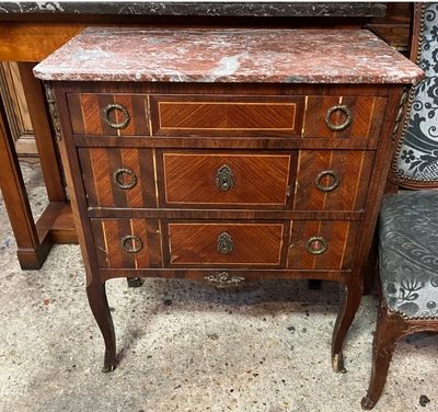 une commode au plateau en marbre, à côté d'un fauteuil