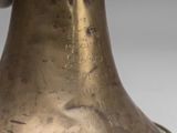 an antique brass bell with a black handle on a white background