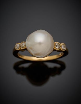 une bague en perles blanches et diamants sur une surface noire