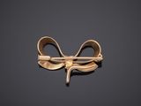 an image of a gold bow brooch on a black background