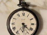 a silver pocket watch with roman numerals on it
