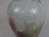 a white vase with red spots on it on a white surface