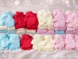 many pairs of baby mittens sitting on a blanket
