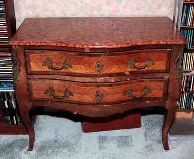 une petite commode en bois devant une bibliothèque