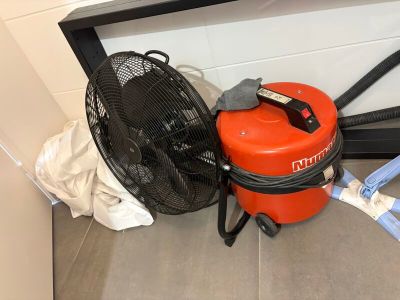un ventilateur rouge posé à côté d'un ventilateur sur le sol