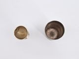 two silver and gold cups on a white surface