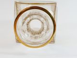 a clear glass vase with a gold rim on a white surface