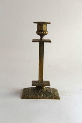 an antique brass candle holder on a white background
