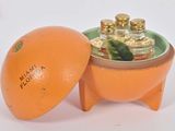 une orange posée dans un bol muni d'un couvercle