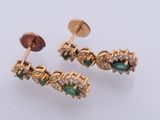 two pairs of emerald and diamond earrings on a white surface