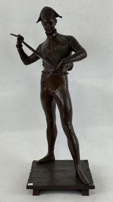 statue en bronze représentant un homme tenant un pistolet, posée sur une estrade en bois