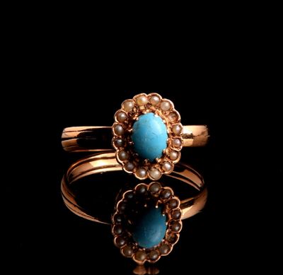 a close up of a gold ring with a turquoise stone