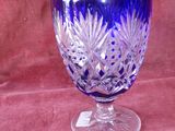 un vase en verre violet posé sur un tissu rouge