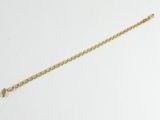une photo d'un bracelet à chaîne en or posé sur une surface blanche