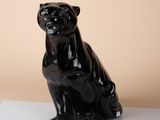 a black statue of a cat sitting on a white surface