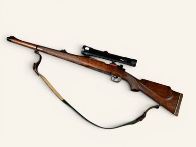an old rifle with a wooden barrel and a sling on a white background