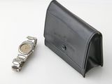 a watch sitting next to a wallet on a table