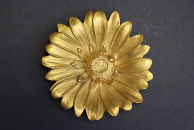 broche en forme de fleur plaquée or sur un fond noir