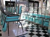 des tables et des chaises dans un snack-bar au sol à carreaux, devant une fenêtre