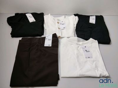 Quatre paires de pantalons pour homme et un t-shirt sont disposés sur une table