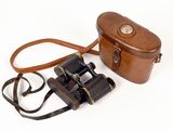 étui à appareil photo en cuir marron et jumelles sur fond blanc
