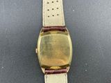 a close up of a watch on a black surface with a brown strap
