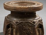 un vieil objet en bois orné de sculptures sur une surface grise