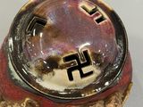 a red and gold bowl with a black cross on it