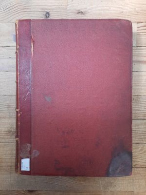 an old red book sitting on top of a wooden table