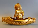 a gold figurine of a woman sitting in a boat